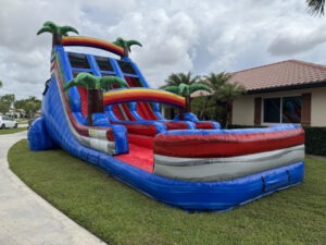 Large blue inflatable water slide with red accents on a lawn in front of a house.